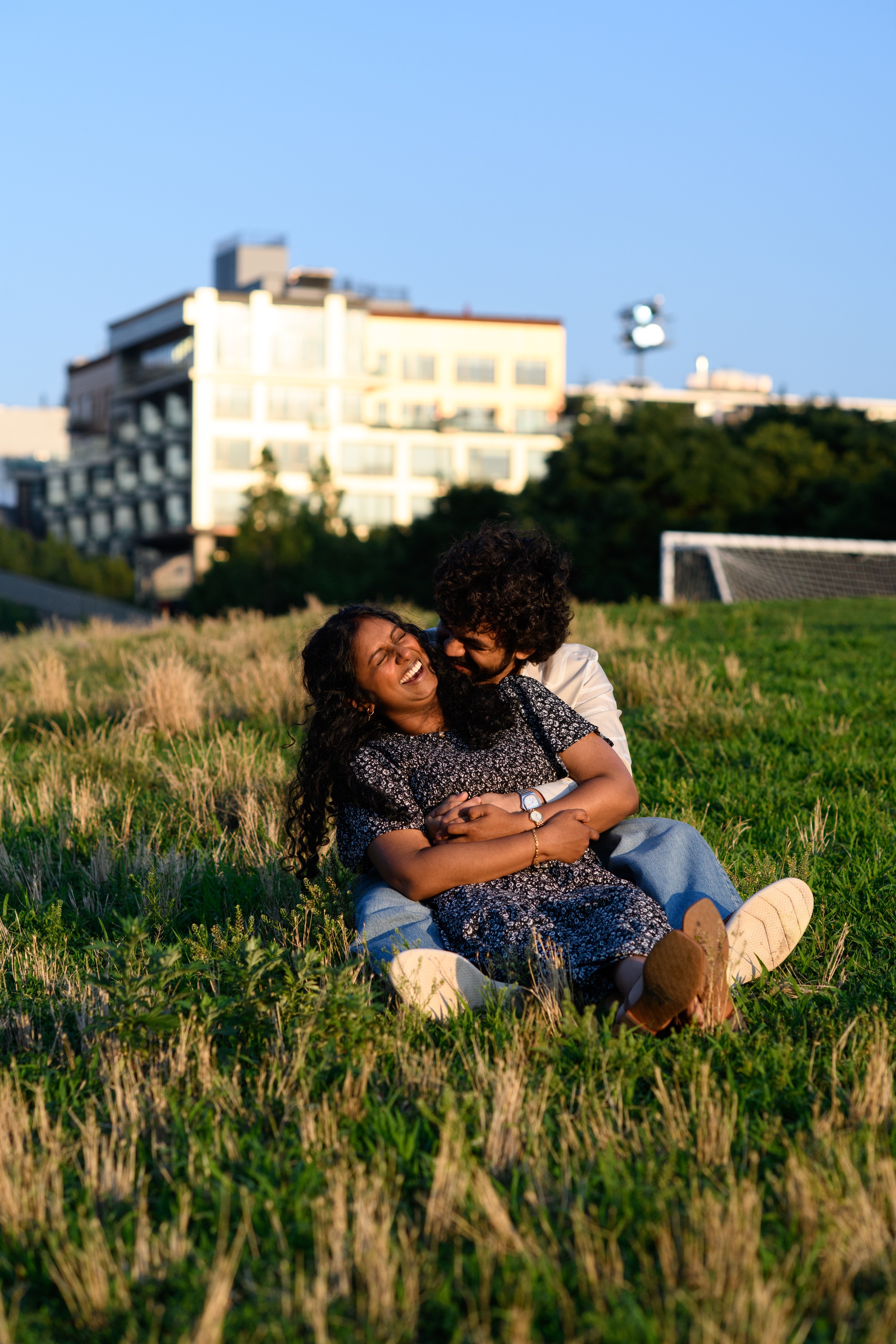 Sanjanaa and Raghu laughing together in a sunlit field