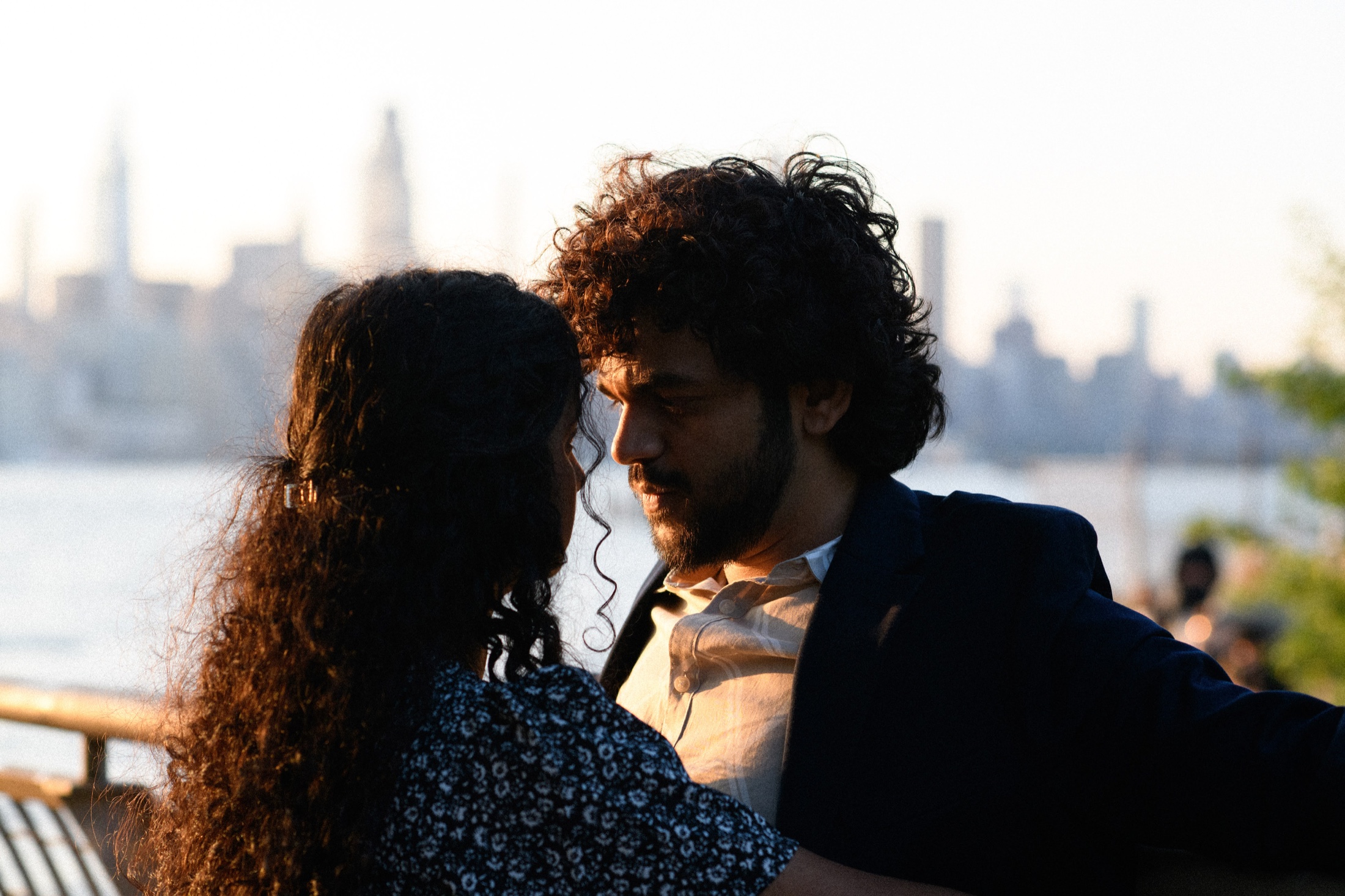 Raghu and Sanjanaa looking into each other’s eyes with the New York City skyline behind them