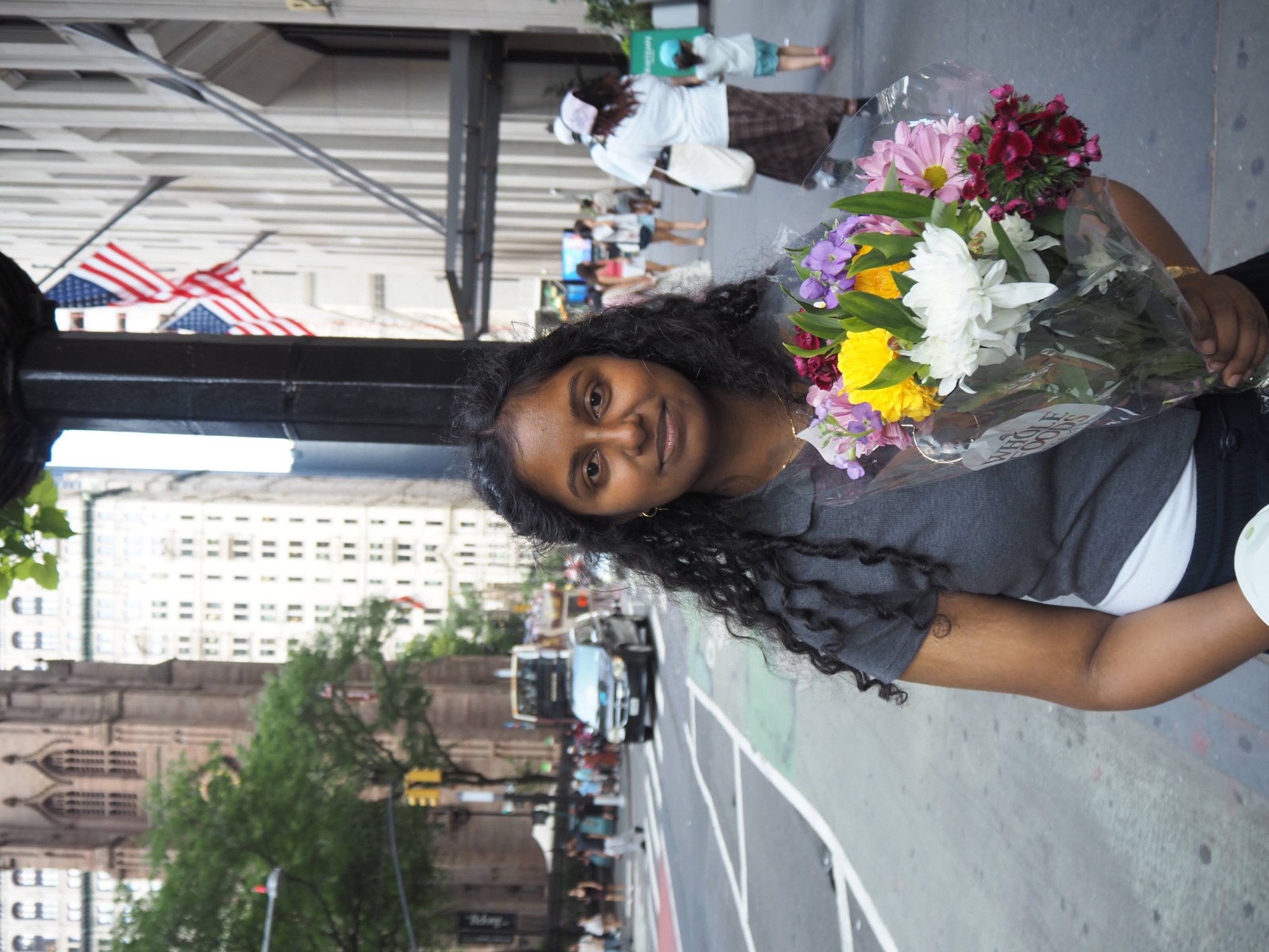 Sanjanaa holding a bouquet of flowers on a New York City street